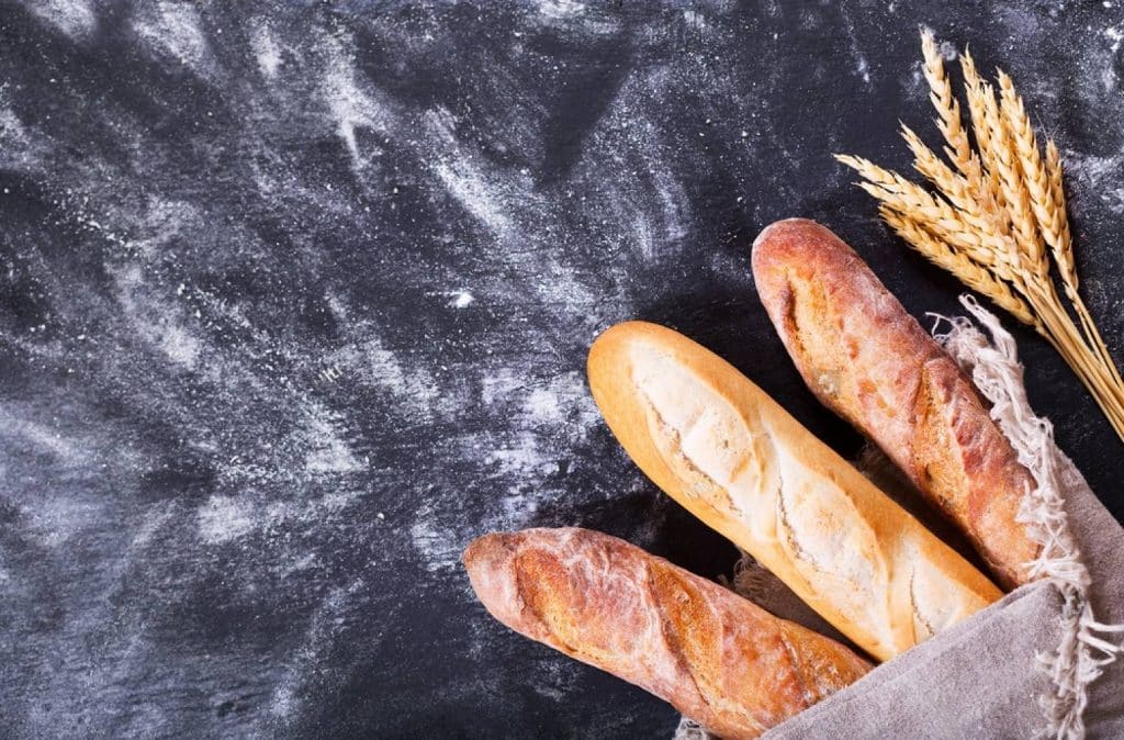 baguette de pain avec un épi de blé et de la farine sur une table