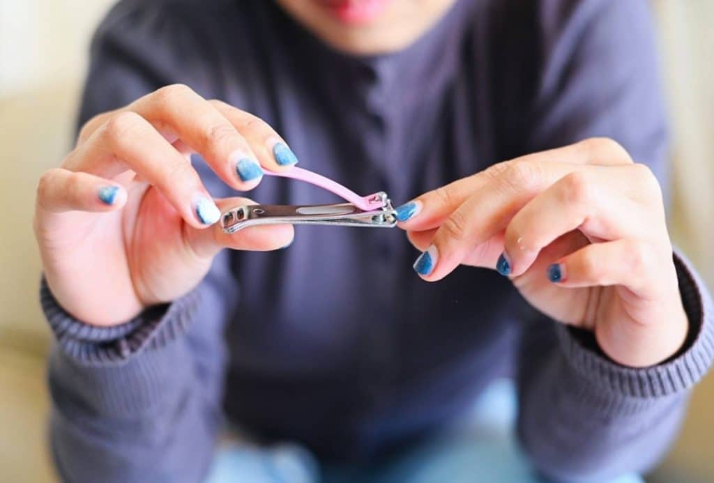 une femme se coupe les ongles