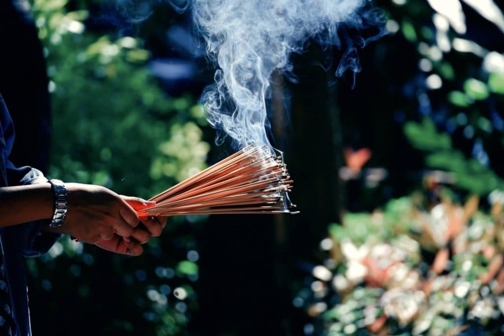 homme tenant des batons d'ancens dans ses mains et priant devant son dieu