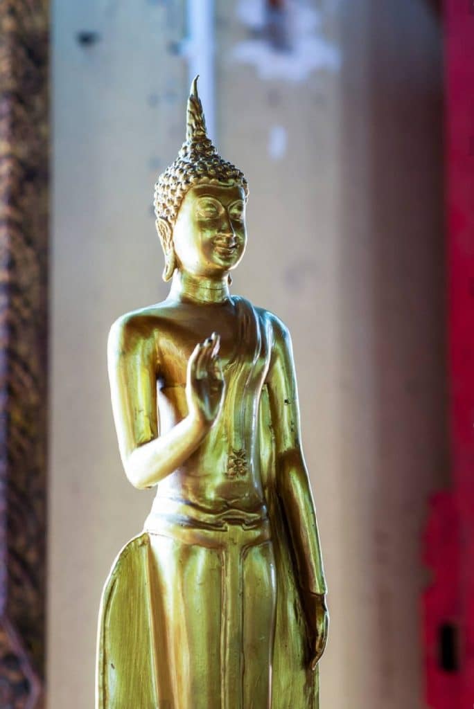 bouddha en or paume de la main tendue et tournée vers l’extérieur.
