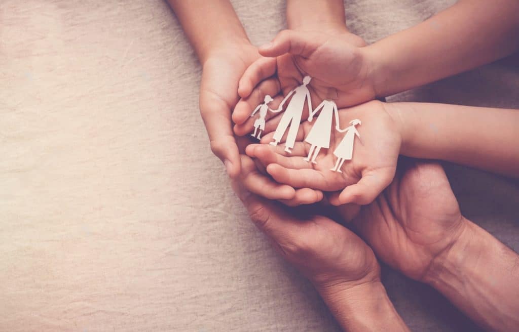 mains d'enfant et d'adulte qui tiennent une famille en papier