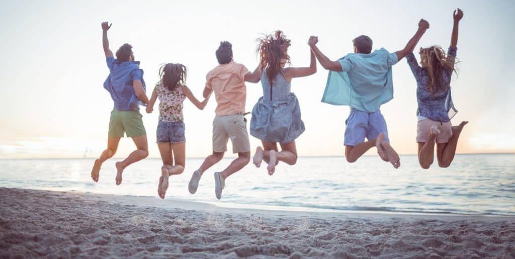 groupe d'amis qui sautent dans le sable