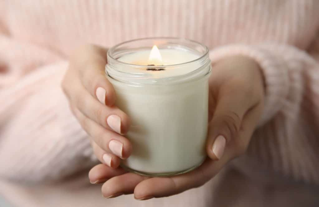 femme qui tient une bougie blanche allumée